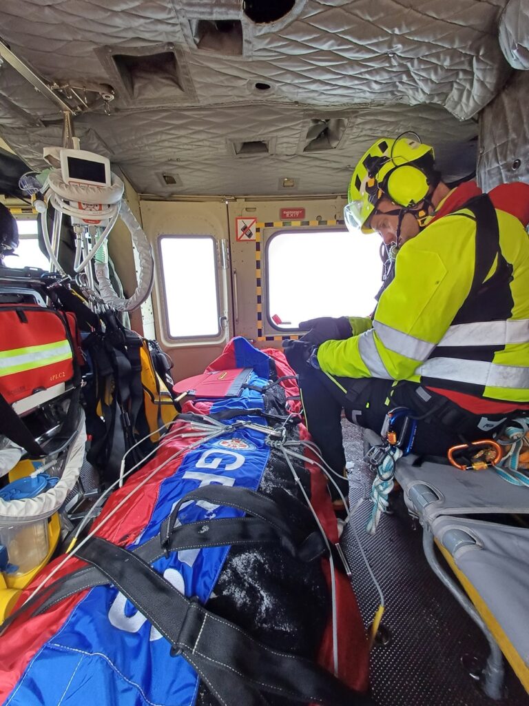reševalec z reševalno vrečo v helikopterju