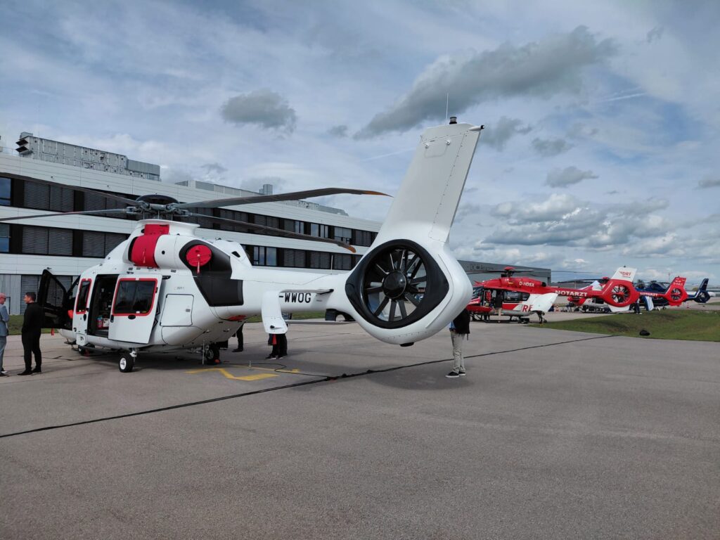 v ospredju je bel reševalni helikopter, v ozadju helikopterji rdeče barve